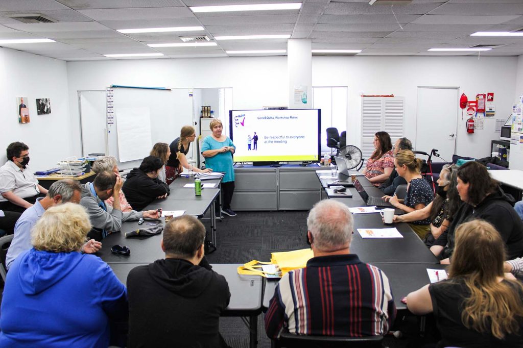 Julie Loblinzk presents at a whiteboard to a group of about 20 people in a conference room